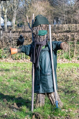 Naklejka premium A scarecrow in a field, with a crow perched on his arm 