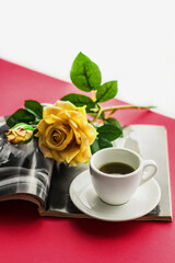 Obraz na płótnie Canvas Romantic atmosphere. A cup of coffee and a rose flower in a magazine on a red background. Happy birthday banner concept, mother's day, valentine's day. Lifestyle.