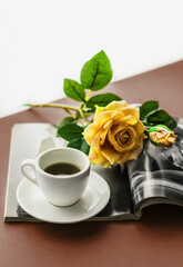 Obraz na płótnie Canvas Romantic atmosphere. A cup of coffee with a saucer and a rose flower in a fashion magazine on a colored background. Happy birthday banner concept, mother's day, valentine's day. Lifestyle. 