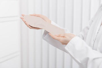 Doctor holding orthopedic insoles in his hands. Orthopedist tests the medical device. Orthopedic insoles on a white. Foot care. Flat Feet Correction. Prevention of flat feet and foot diseases