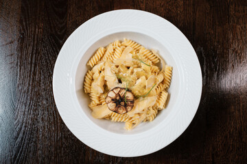 Pasta with cheese and herbs garnished with fried garlic.