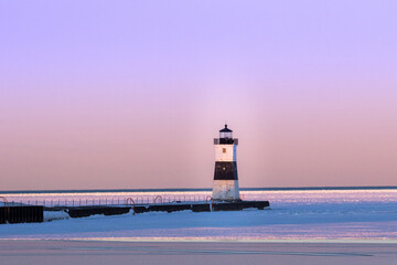 lighthouse on the shore of lake, purple sky as sunsets, frozen lake with floating icebergs 