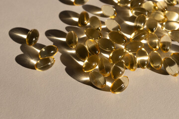 Fish oil capsules with omega 3 and vitamin D.Gold capsules on beige background.Fish oil capsules on beige background, source of vitamin D, selective focus. Omega 3