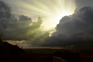 Cloudscape image of dark stormy clouds in blue sky with sun beam. The rays of the sun after the...