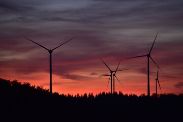 Fototapeta na wymiar Windkrafträder in einem Windpark mit Abendrot und dunklen Wolken