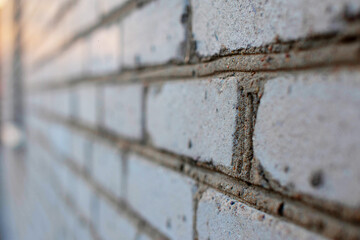 Close-up of the cement between the bricks of the house. Sunset. Gray brick building. Close-up of the seam between the bricks.