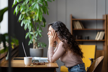 Bored young girl student tired of learning sit in library looking at laptop sad and unhappy. Lazy...