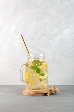 Refreshing summer drink. Mojito cocktail with lemon, lime and mint in jar. Homemade iced lemonade. Grey background, copy space