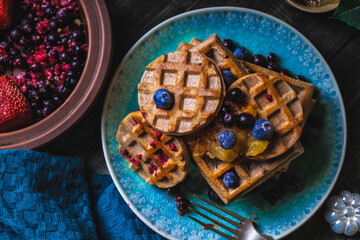 Croissant Waffle or Croffle with srawberry and blueberry sauce served in plate and dark background. Close up, copy space.