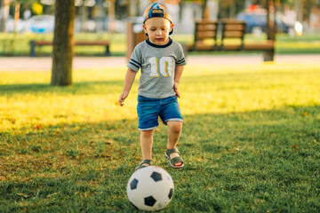 little boy playing football on the soccer field on a sunny day. Healthy leisure of preschool children