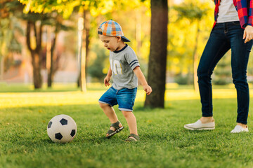 Happy family. Mother with son having fun playing football together on the grass on a sunny summer day