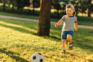 little boy playing football on the soccer field on a sunny day. Healthy leisure of preschool children
