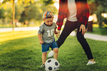 Happy family. Mother with son having fun playing football together on the grass on a sunny summer day