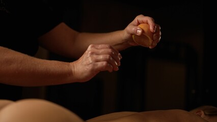 Use of oranges during massage. Female therapist using orange during back massage at the spa. Oranges are squeezed on the female body during the massage.