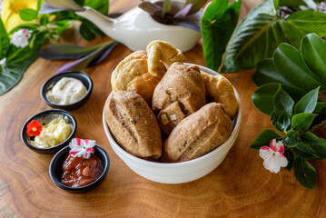 Homemade Brazilian wholegrain breads in a white bowl on a blurred wooden background.