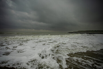 dramatic sky over the black sea with waves, clouds and stones
