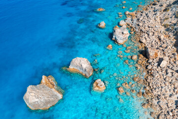 Aerial view of clear blue sea, stones and rocks in water, empty beach at sunset. Summer in Lefkada island, Greece. Tropical seascape with azure water. Top view of sea coast. Nature background. Travel