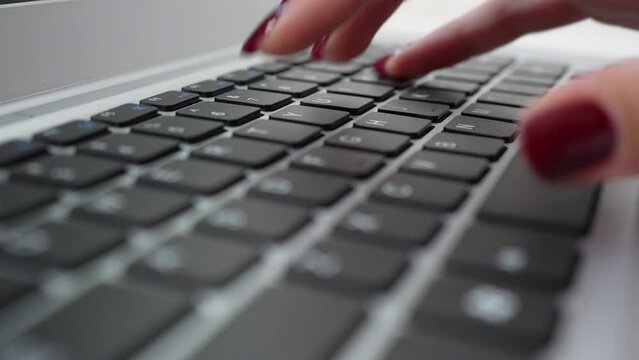 Laptop keyboard, female fingers with manicure typing text on it, tracking shot. Extreme closeup copywriter or office manager at work. Concept of business