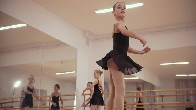 Ballet training - ballerina girls in black dresses dancing in the studio