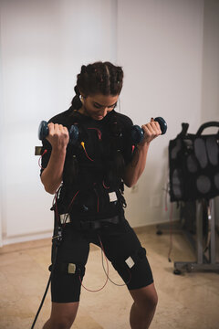 A girl exercising with an electrostimulation vest in a clinic.