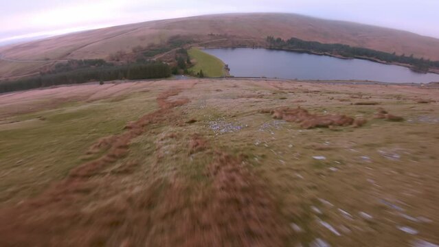 Aerial drone shot of Brecon Beacons with reservoir at the botom next to pen y fan peak. Drone video of fast flowing fpv view wales uk