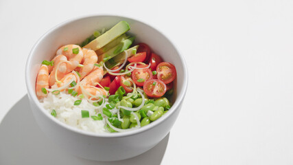 Poke bowl with red shrimps, rice, tomatoes and edamame beans in the bowl.Top view. Closeup.