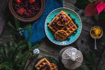 Obraz na płótnie Canvas Croissant Waffle or Croffle with srawberry and blueberry sauce served in plate and dark background. Close up, copy space.