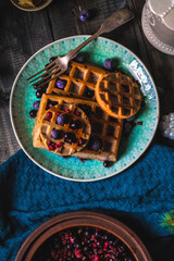 Croissant Waffle or Croffle with srawberry and blueberry sauce served in plate and dark background. Close up, copy space.