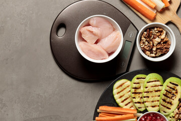pieces of raw meat on kitchen scales, grilled vegetables, nuts and vegetable sticks. Close-up, top...