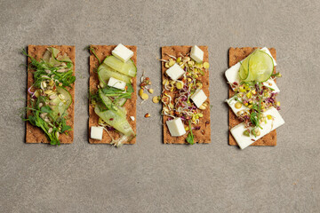 four rye crisps with sprouts, micro-greens, tofu or cheese. Close-up, top view on gray background