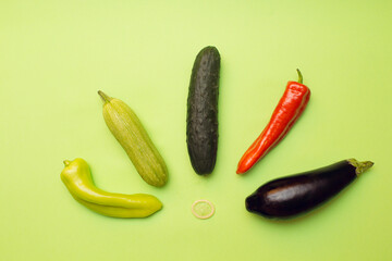 red and green peppers, cucumber, zucchini, eggplant, condom on green background
