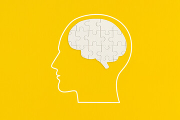 Human head with puzzle on yellow background
