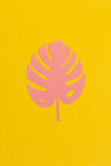Tropical pink paper leaves on yellow background.Summer concept. Top view, flat lay.