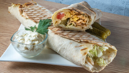Shawarma chicken roll. Fresh roll of thin lavash or pita bread filled with grilled meat, cheese, carrots, sauce, green.