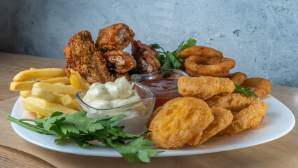 Snack platter - cheese sticks, chicken nugget, onion rings, french fries mix of snacks and sauces . Beer board.