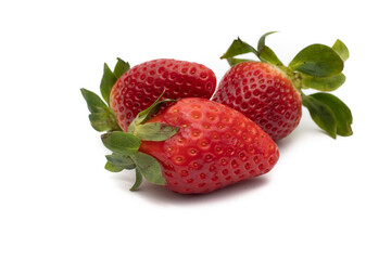 Three whole strawberries with their green leaves isolated on white background.