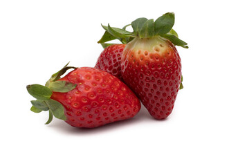 Three whole strawberries with their green leaves isolated on white background.