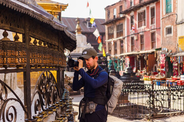 A tourist photographs prayer wheels in Swayambhunath, Nepal