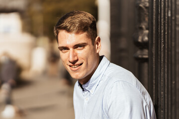 a blond-haired, blue-eyed man looks at the camera with a smile on his face