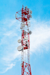 Telecommunication tower with radio relay communication antennas and 4G, 5G transmitters. Cellular base station with transmitter antennas on a high red and white metal telecommunication tower.