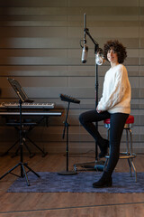 A young curly hair singer woman recording a song in a real studio. Vertical photo