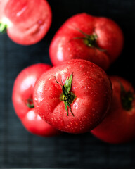 Ripe homemade tomatoes on a black background with water drops