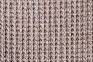 Texture of knitted woolen fabric of light brown color.