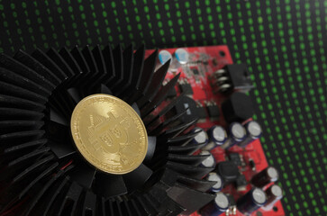 A bitcoin gold coin on a cooling fan against the background of binary code