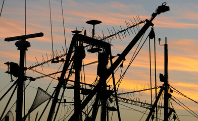 silhouettes of moored fishing vessels in Lakes Entrance at sunset.
