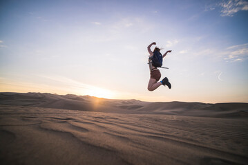 Woman jumping at sunset in the desert at Huacachina, Ica Region, Peru, South America