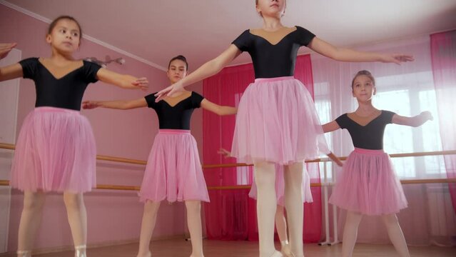Four ballerina girls in beautiful dresses practicing ballet dancing