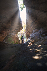 A man inside a cave with light coming through with a sign in Thai which means a cave with a large hole. This cave is at a wildlife sanctuary in Kalasin Province, Thailand.