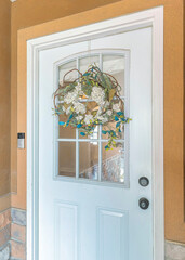 Vertical White front door with wreath over the glass panels and doorbell with camera