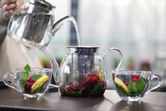 Pouring boiling water into tea. Fruit berry tea in a glass teapot